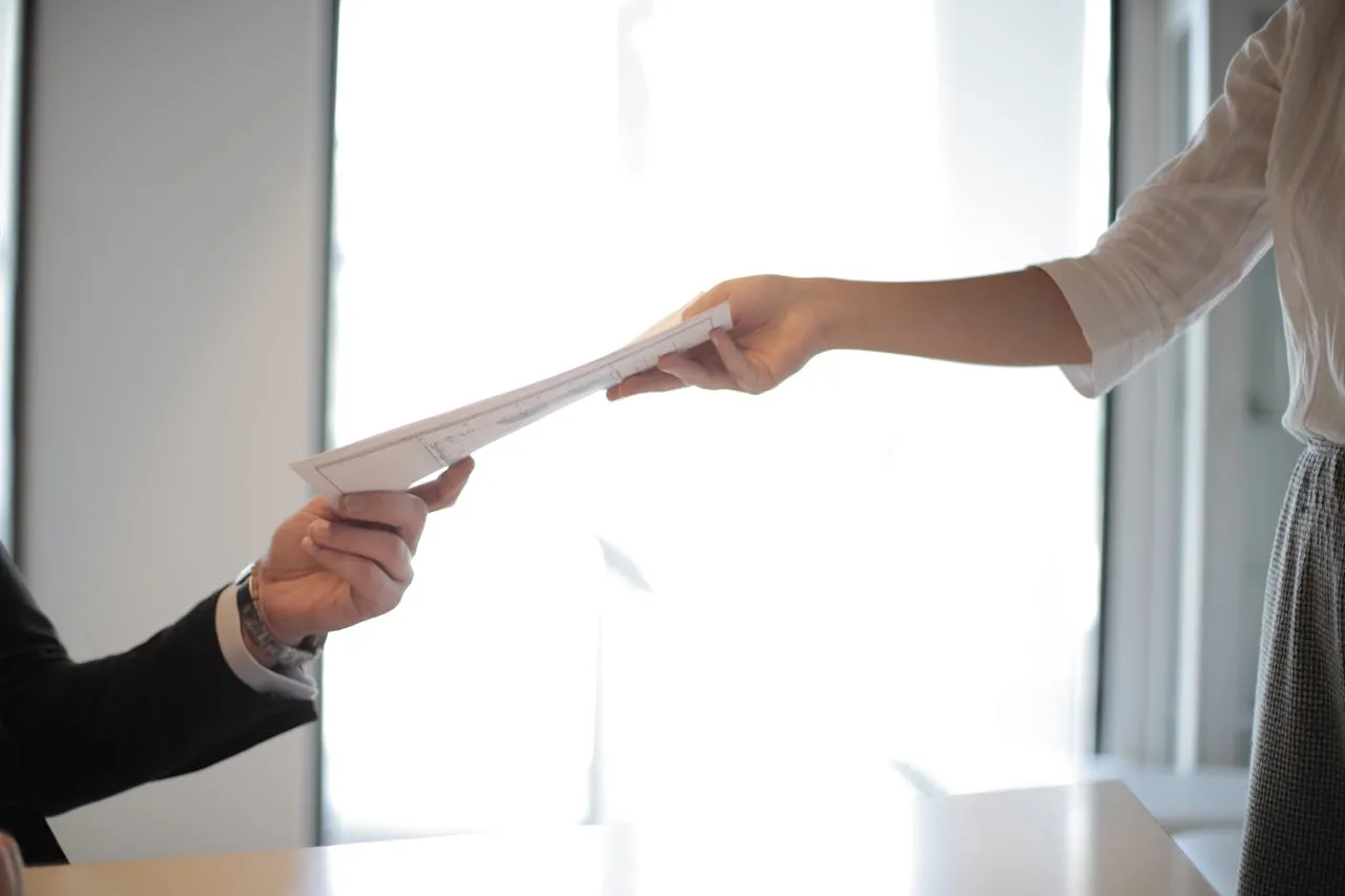 Employee hands business document to someone.