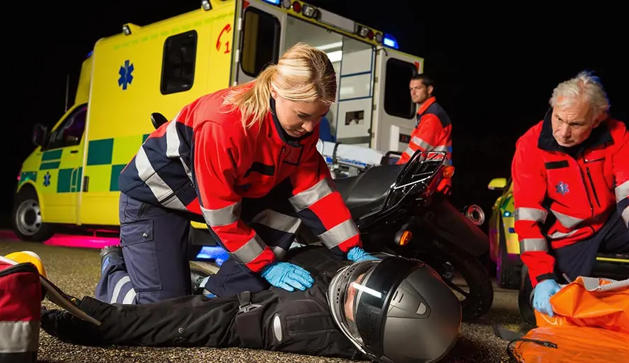 EMT helps an injured motorcyclist.